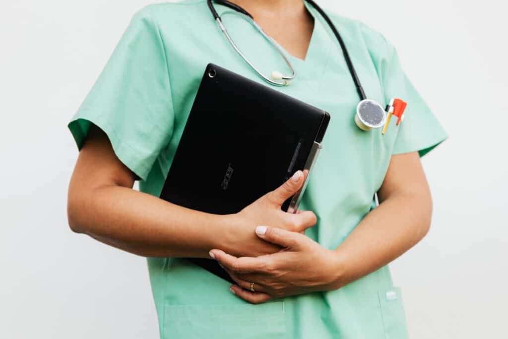 Sterile Processing Technician Job Description: What Every Hospital Must Include to Hire, Develop, and Retain SPD Staff 2 Close-up of a nurse in green scrubs holding a tablet and stethoscope, symbolizing modern healthcare.